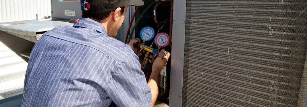 HVAC technician servicing a condenser unit in Fallston
